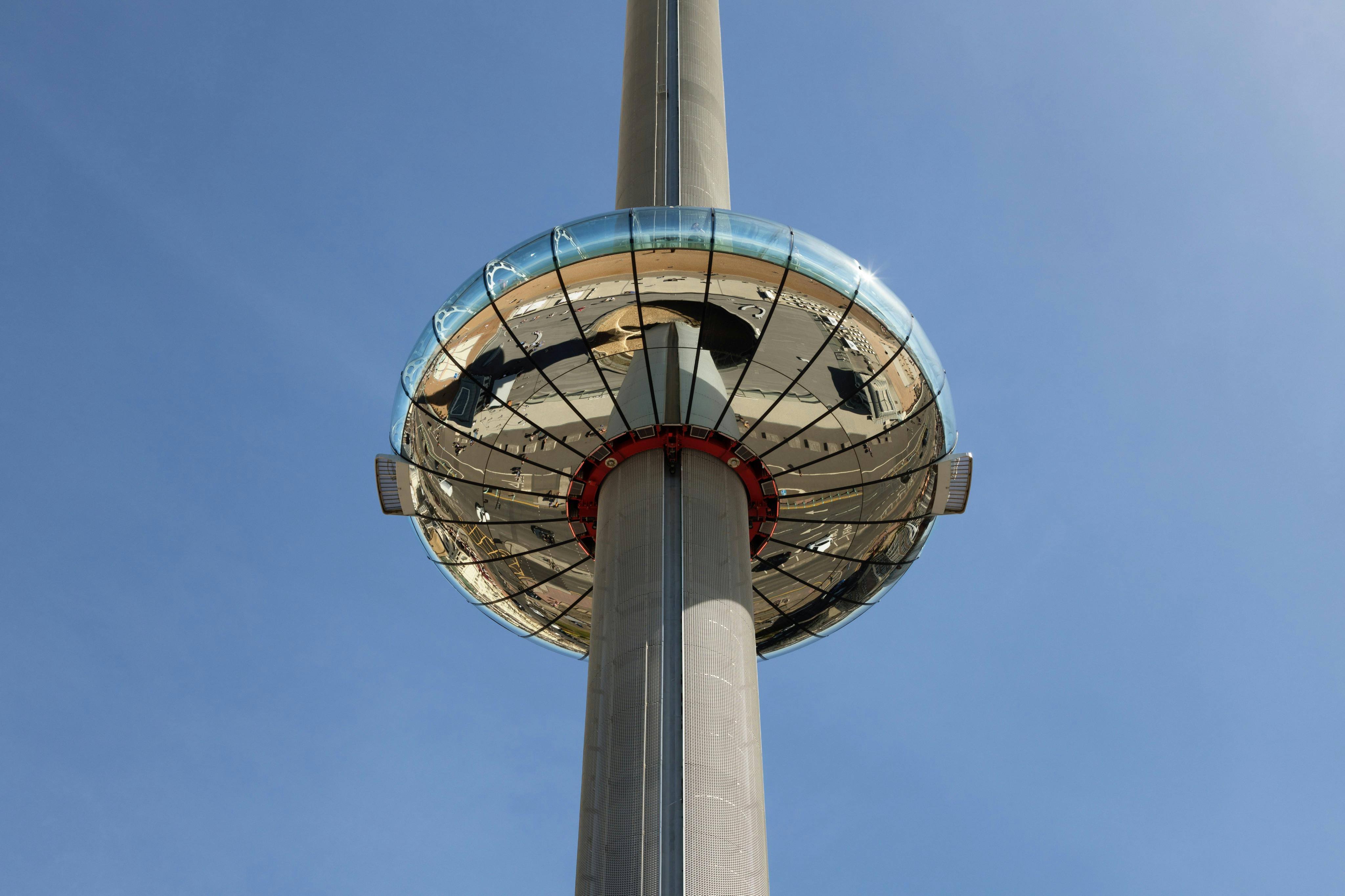 A tall observation tower with a glass-enclosed circular viewing platform, set against a clear blue sky.