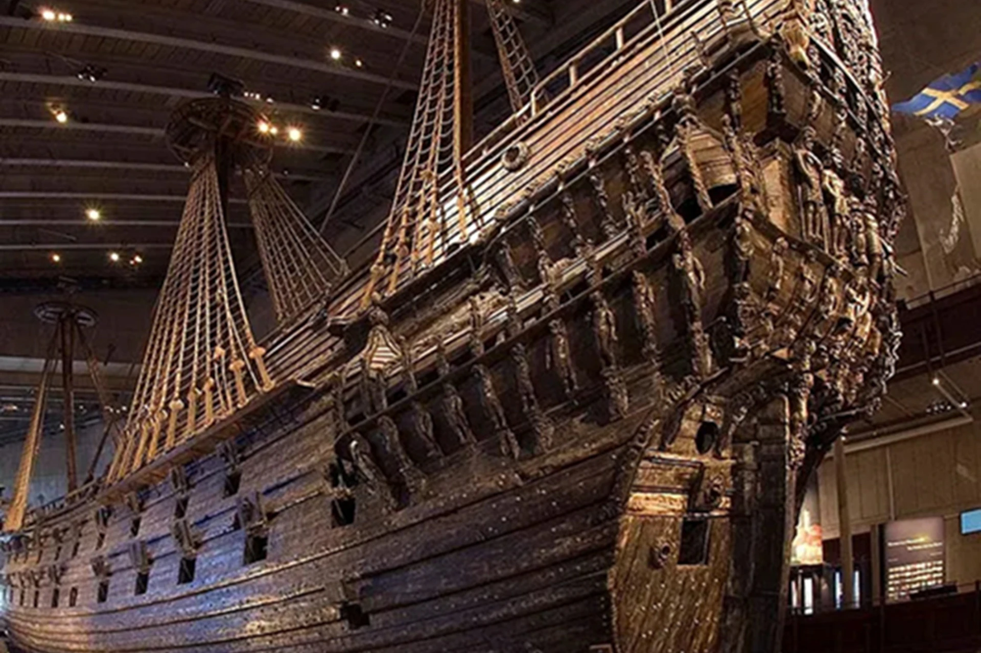 A large, well-preserved wooden ship displayed indoors, showcasing intricate carvings and rigging under museum lighting.