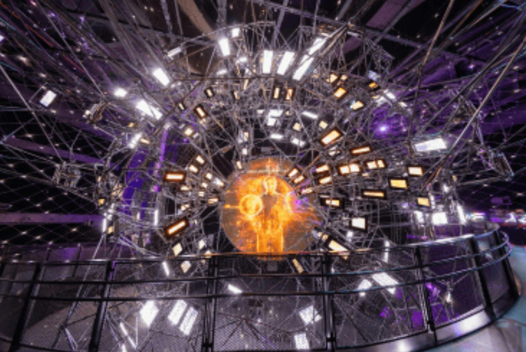 A circular structure with lights and an orange glowing center, resembling a futuristic installation in a dark space.