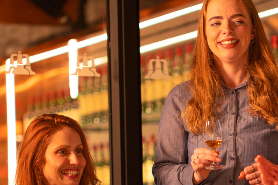 A group of four people enjoying drinks and conversation at a bar with bottles and glasses on the counter.