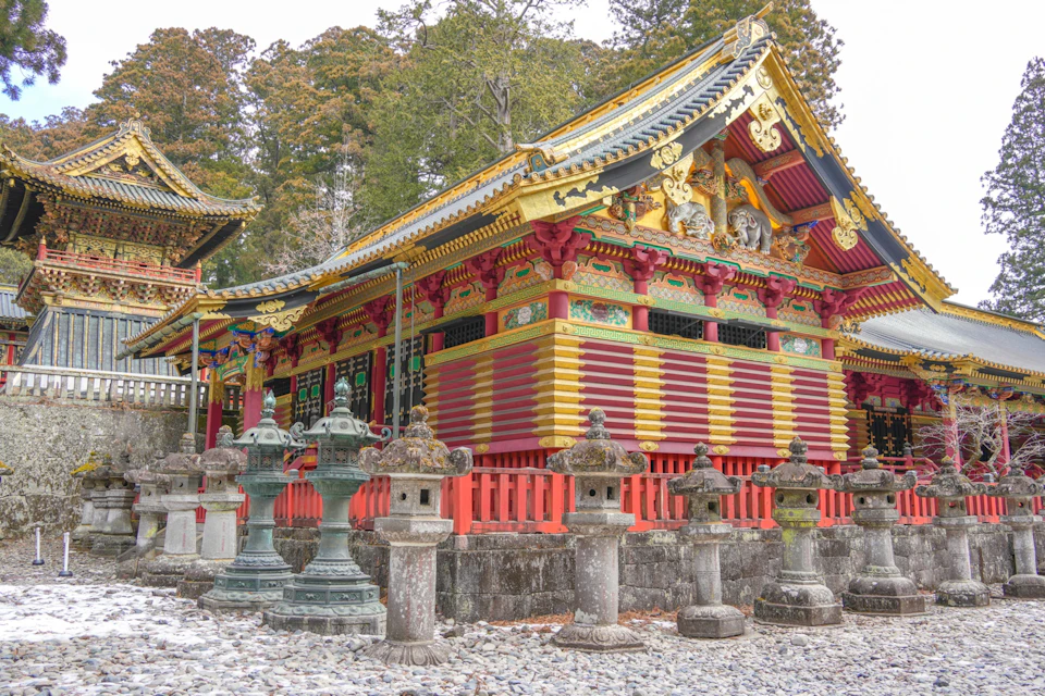 A colorful traditional Japanese building with ornate details and stone lanterns in the foreground.