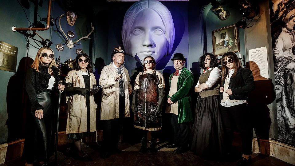 Cyber punk costumed people in creepy front of large statue of Mary Shelley's head
