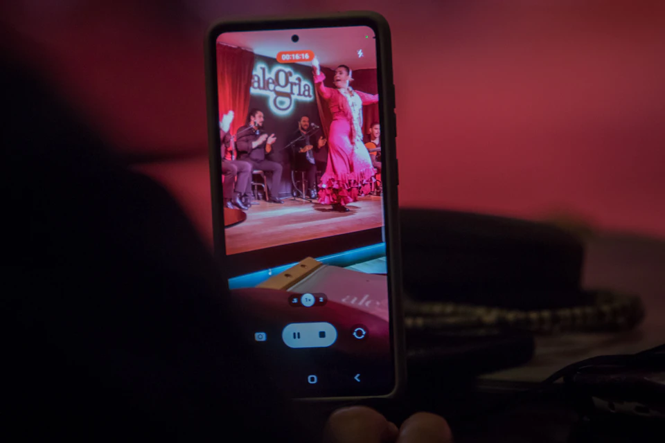 Camera in action in 'Alegria' Malaga, capturing the dancer and the audience enjoying flamenco with wine in hand.
