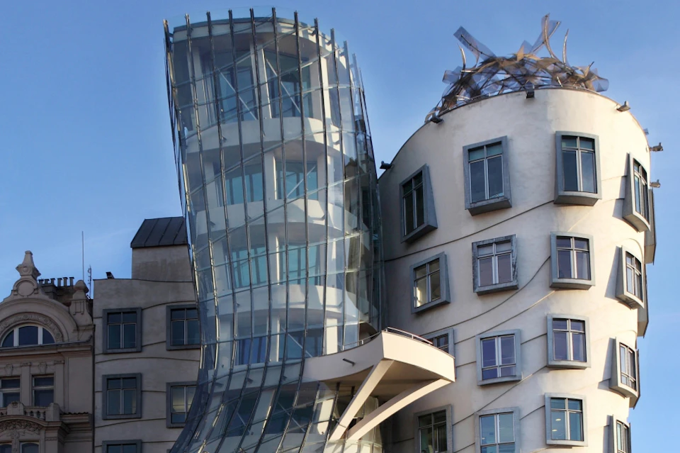Two modern, uniquely shaped, interconnected buildings with numerous windows and a curving glass facade under a clear sky.