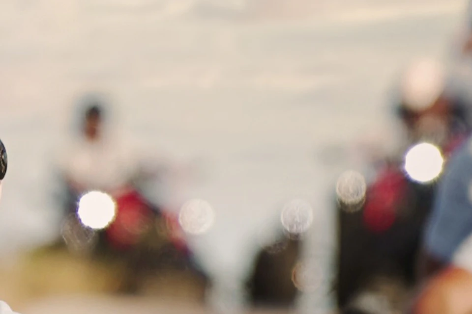 Group of people riding three-wheeled motorcycles on a paved road, wearing helmets and sunglasses, with a scenic background.