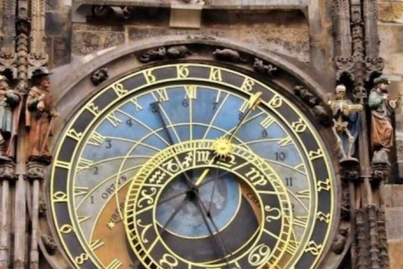 歴史的な建物のファサードにカラフルなダイヤルと詳細な彫刻を備えた華やかな天文時計のクローズアップ。