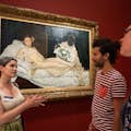Guide explaining Manet's painting Olympia to two guests