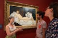 Guia explicando o quadro Olympia, de Manet, para dois convidados