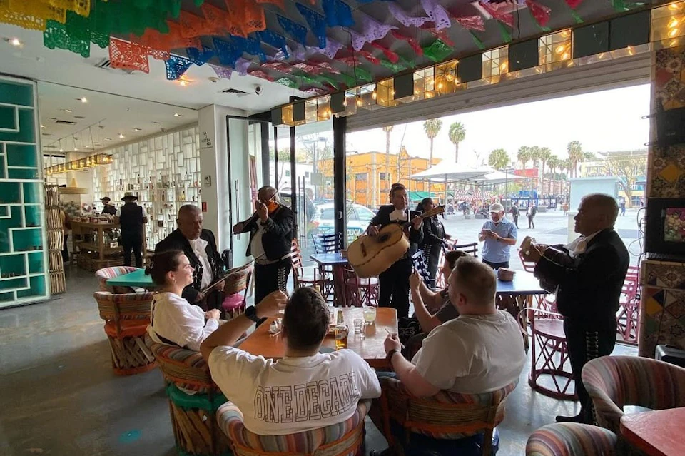 Customers enjoying drinks with mariachi.