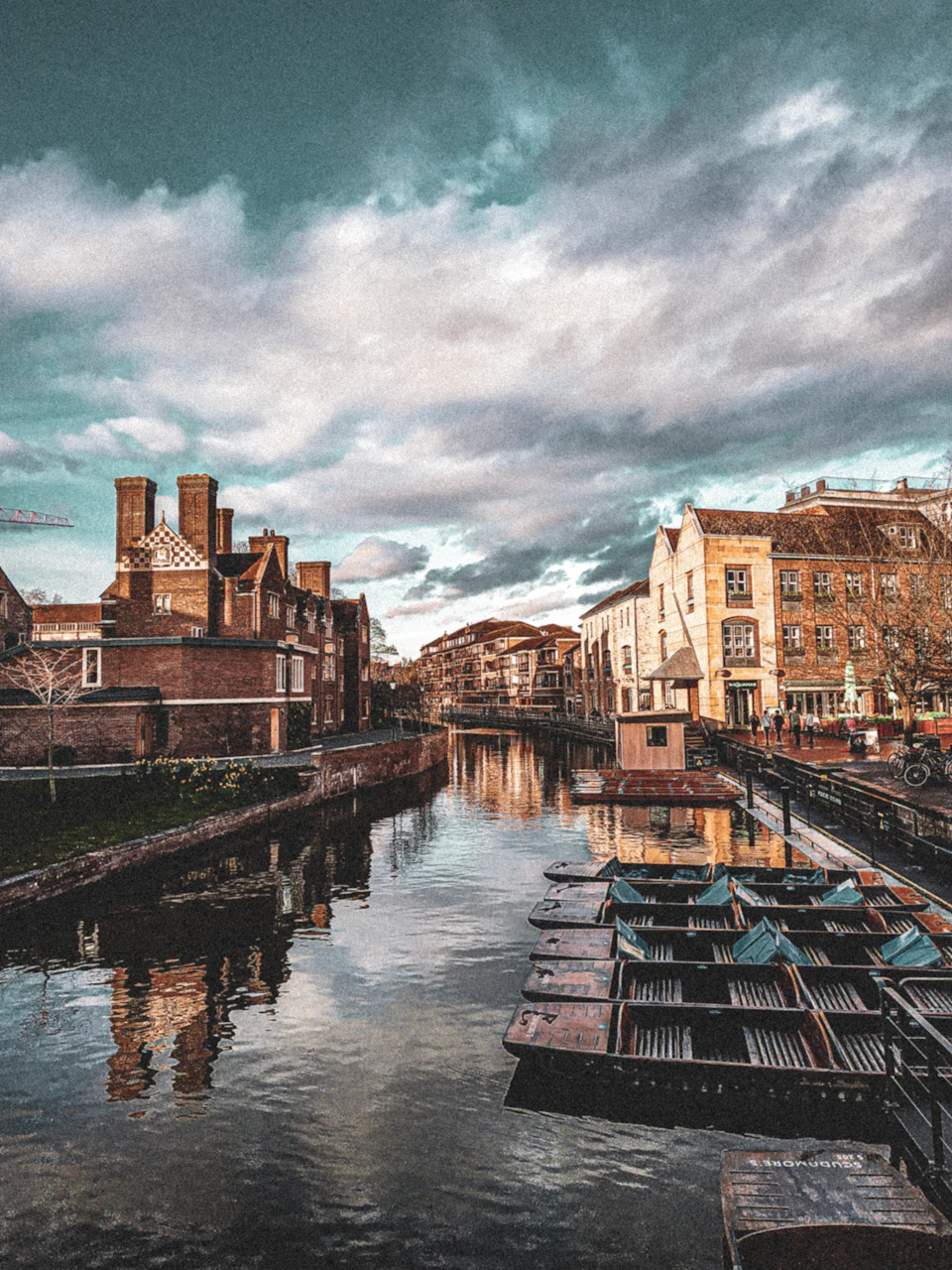 Boats lined up on a canal with historic buildings on both sides under a cloudy sky.