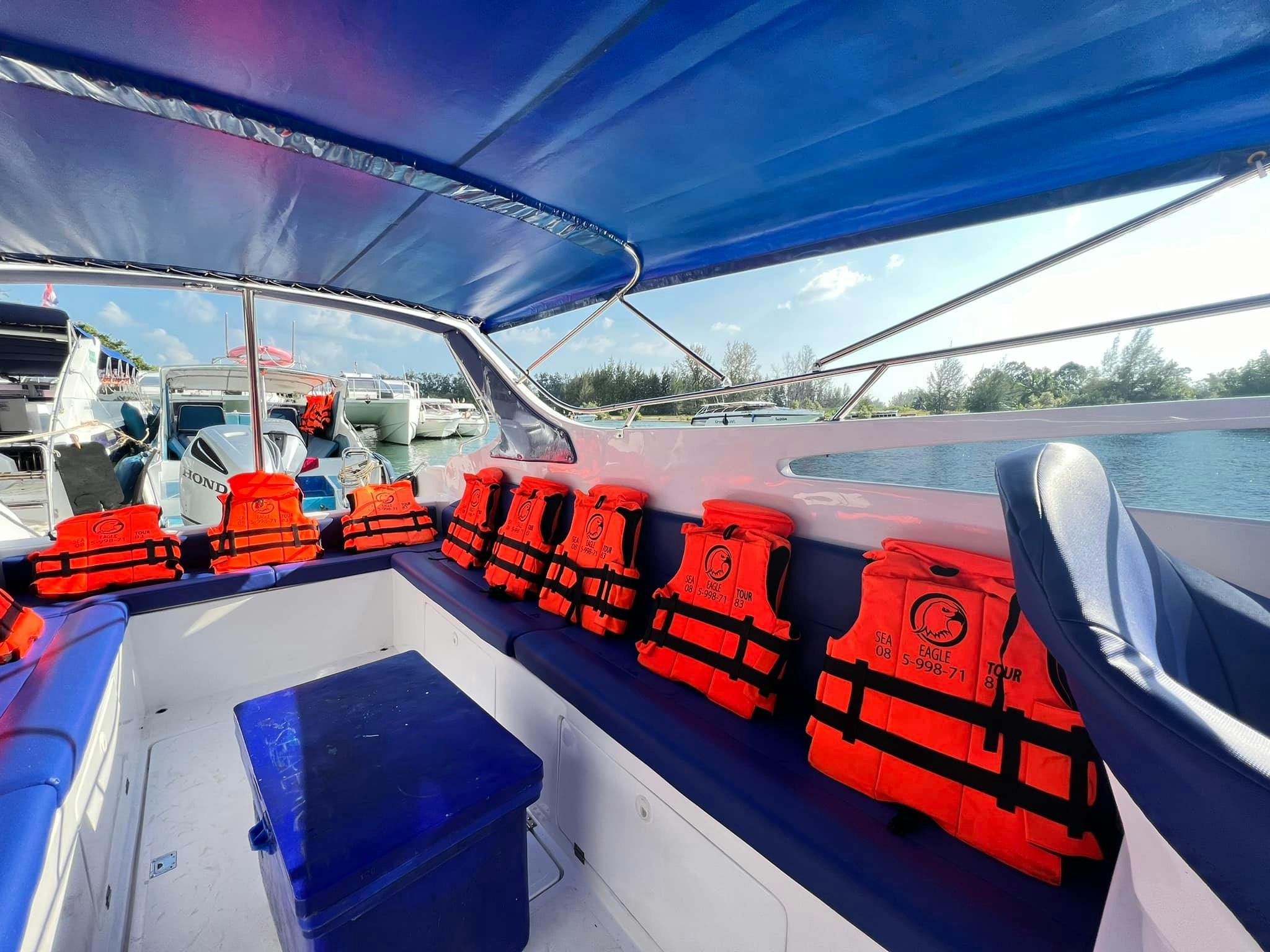 Το εσωτερικό ενός σκάφους με πολλαπλά κόκκινα σωσίβια παρατάσσεται σε έναν μπλε πάγκο κάτω από ένα μπλε θόλο, ανοιχτό νερό ορατό έξω.