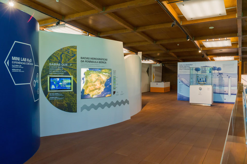 Modern exhibit hall featuring display boards with maps and information about the Iberian Peninsula's hydrographic basins.