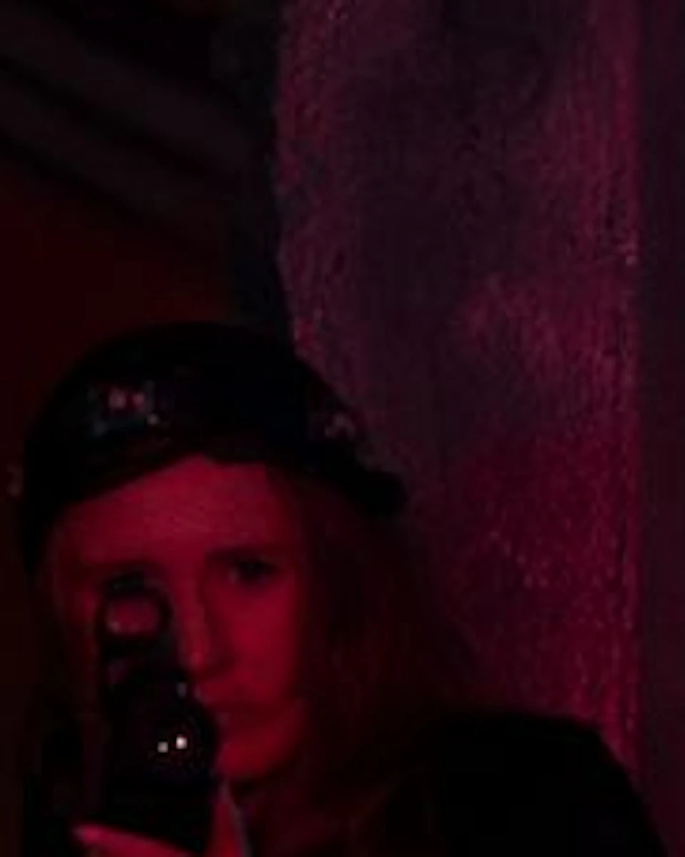 Four people are playing laser tag in a dimly lit arena with red and blue lighting, holding laser guns and wearing headbands.