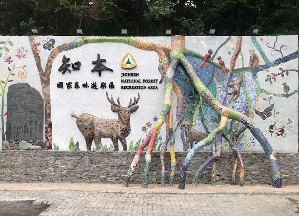 A decorative wall at Zhiben National Forest Recreation Area featuring mosaic art of deer and colorful tree roots.