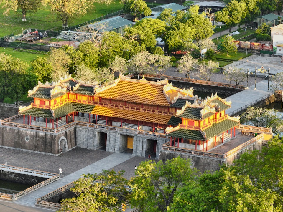 An aerial view of a traditional East Asian building with ornate roofs, surrounded by trees and pathways.
