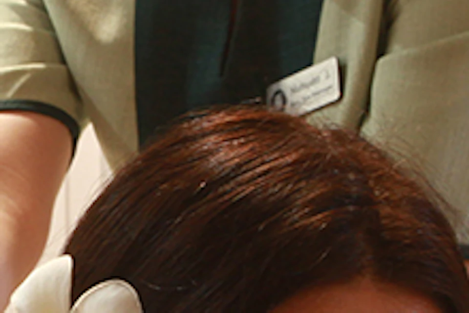 A woman receiving a back massage from another woman in a spa setting, with towels and a flower accent.