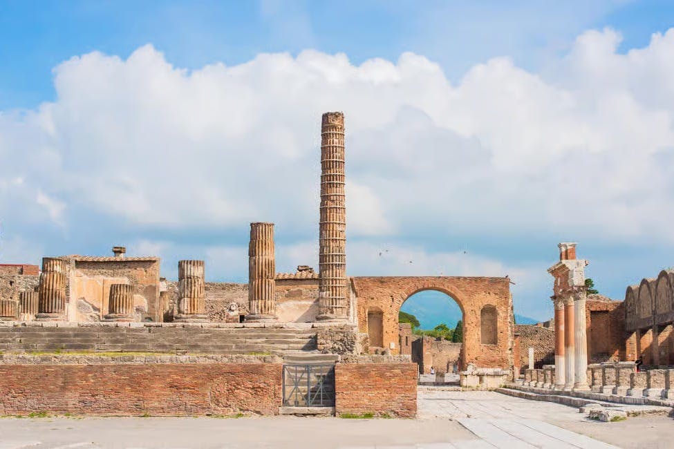 在部分多云的天空下，有柱子、拱门和石头结构的古代遗址。