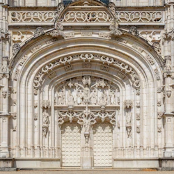 Utsmyckad katedralentré med invecklade gotiska stenhuggningar, statyer och två stora välvda dörrar.