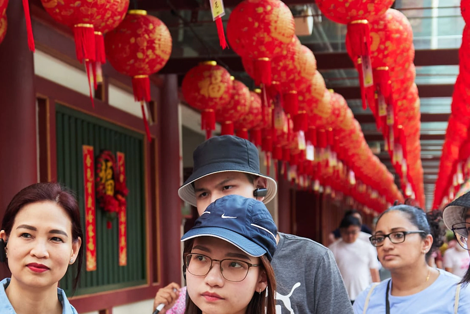 A tour guide speaking to a group of tourists under a walkway decorated with red lanterns.
