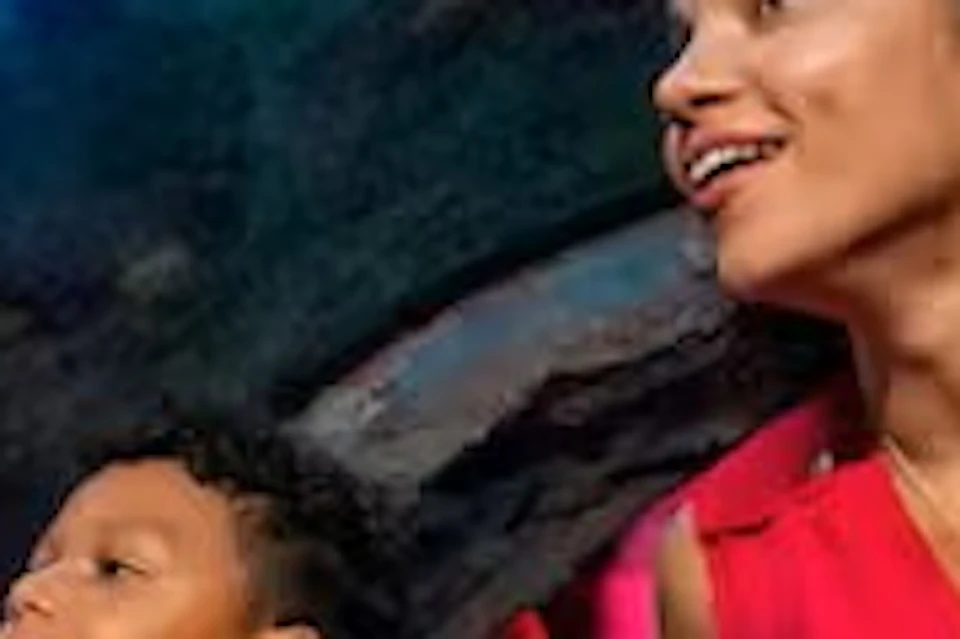 A woman and a child inside an underwater tunnel in an aquarium, looking up at fish and rays swimming above.