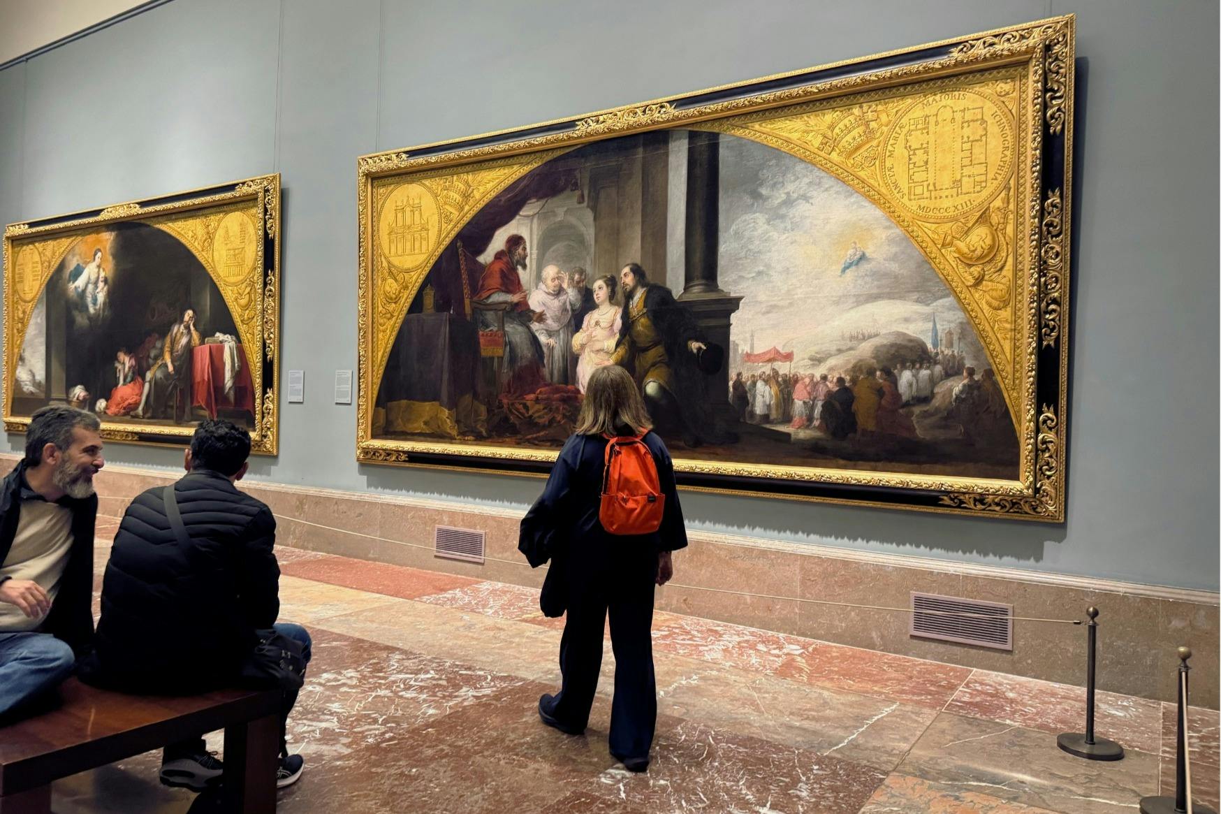 金色の建築要素に囲まれた壮大な祭壇画の前で、訪問者が立ち止まります。