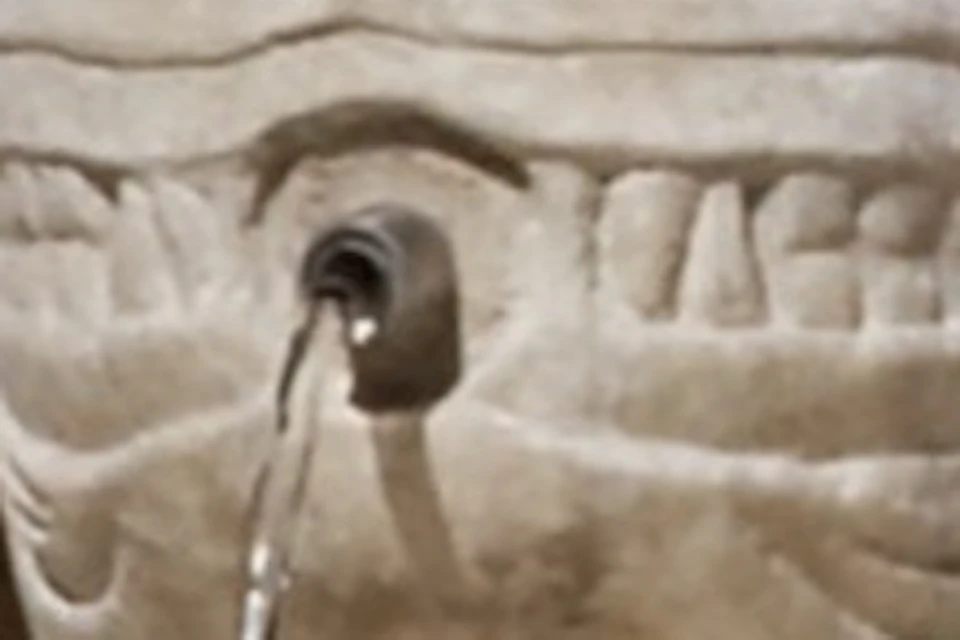 A stone fountain surrounded by sculpted lion figures, located within an ornately decorated courtyard.