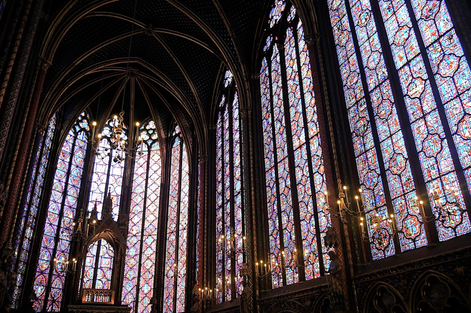 Ornate Gothic-style interior featuring tall stained glass windows and intricate architectural details.