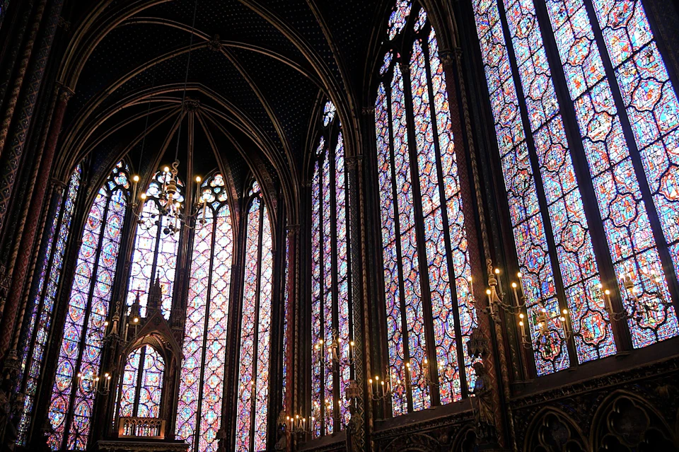 Ornate Gothic-style interior featuring tall stained glass windows and intricate architectural details.