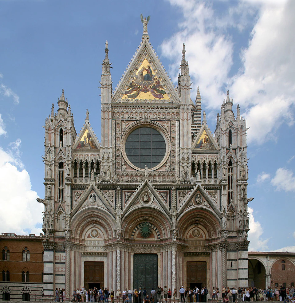 Facade of a Gothic cathedral with ornate details, three large doors, and a rose window. Crowds stand at the entrance.