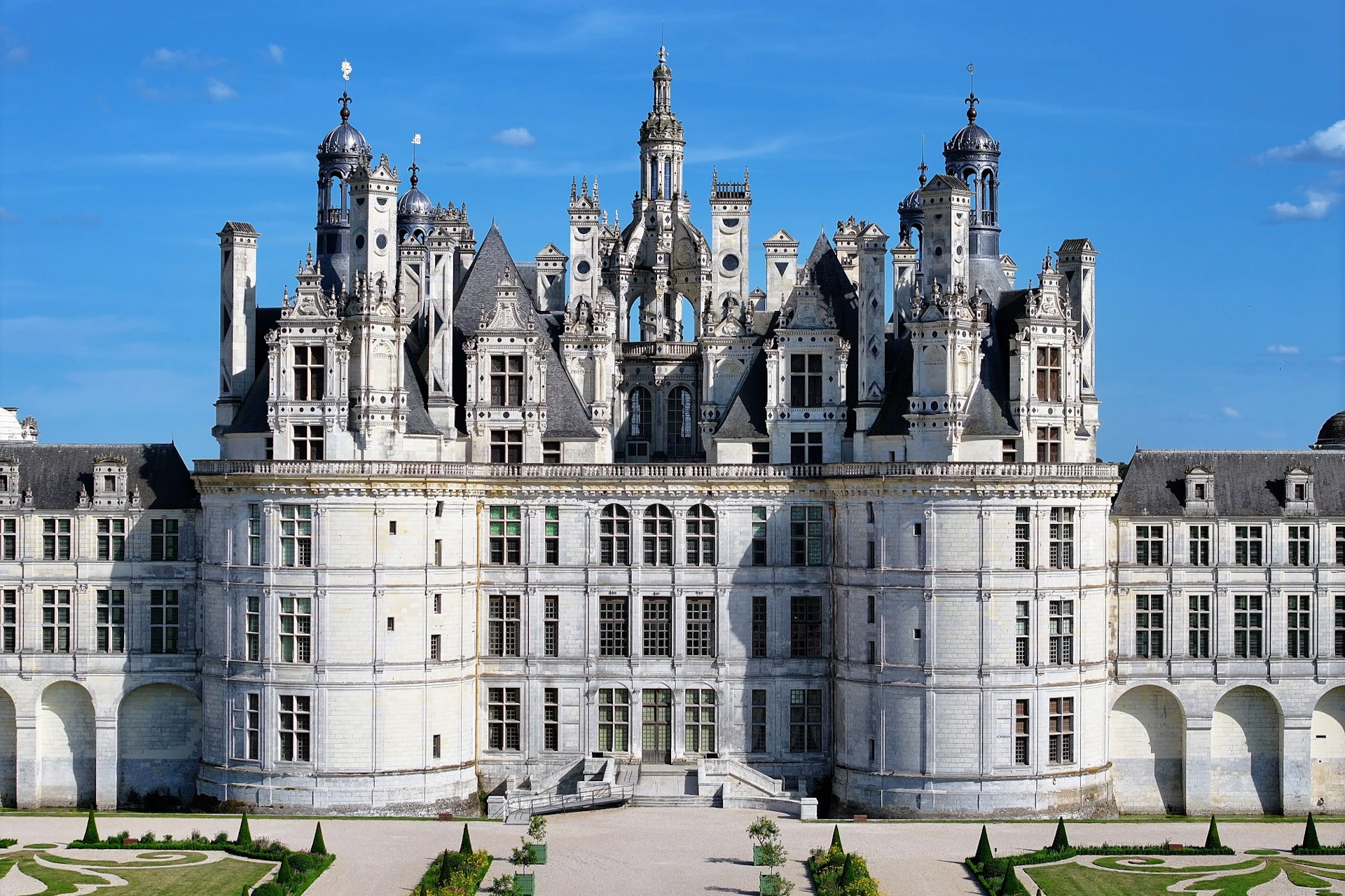 A grand, symmetrical castle with ornate towers and spires, shown under a clear blue sky.