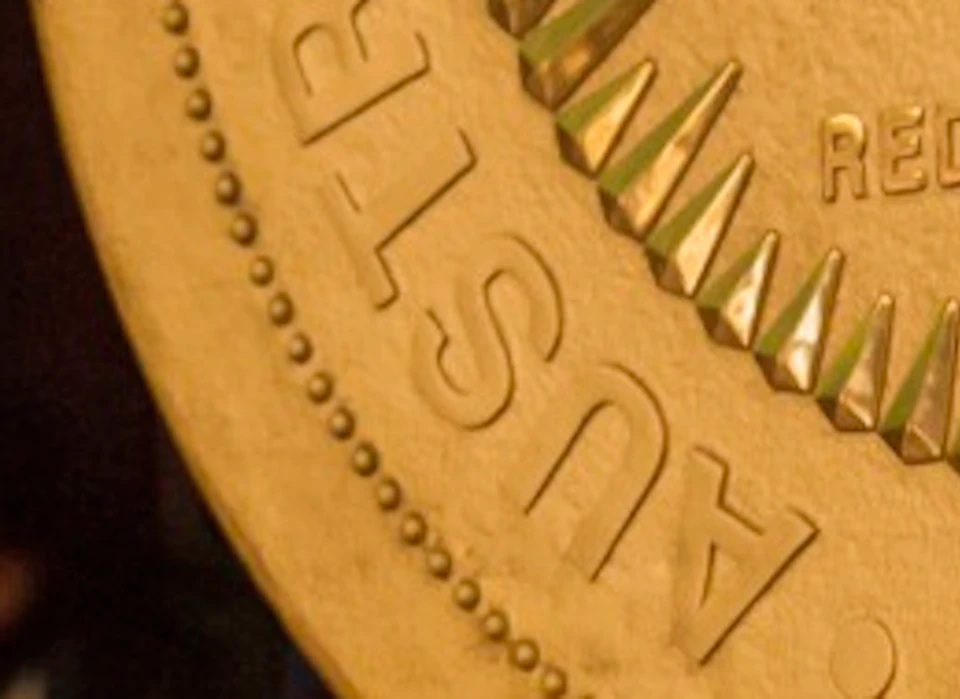 A group of people observing a large display of a gold coin featuring a kangaroo, with dim indoor lighting.