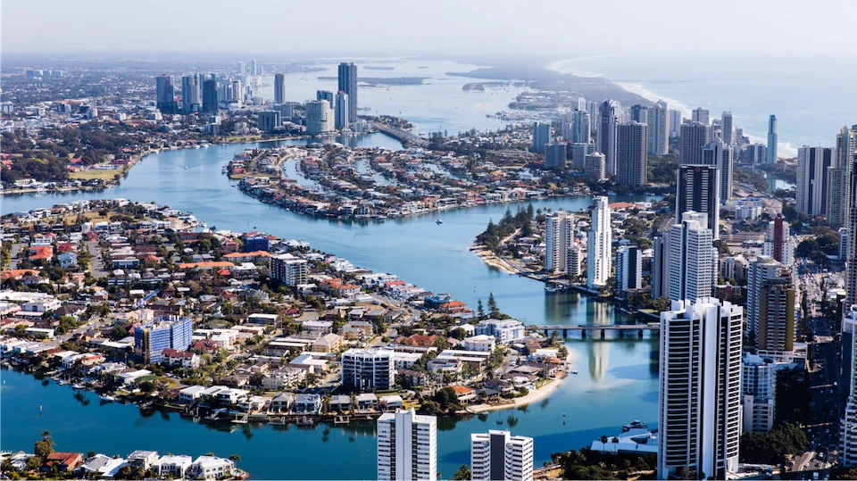 Aerial view of a city with numerous high-rise buildings, waterways, and residential areas on a clear day.