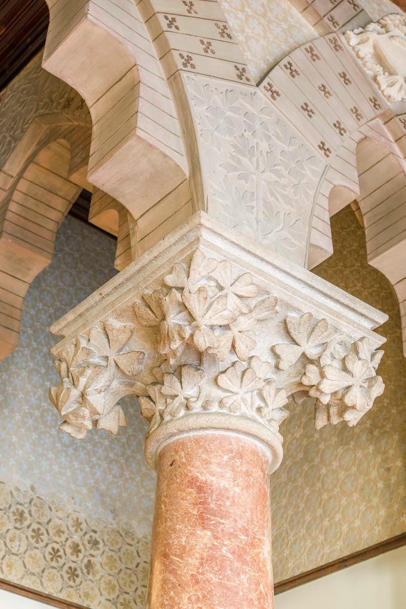 Une colonne de pierre ornée de sculptures florales détaillées soutient une arche aux motifs complexes.