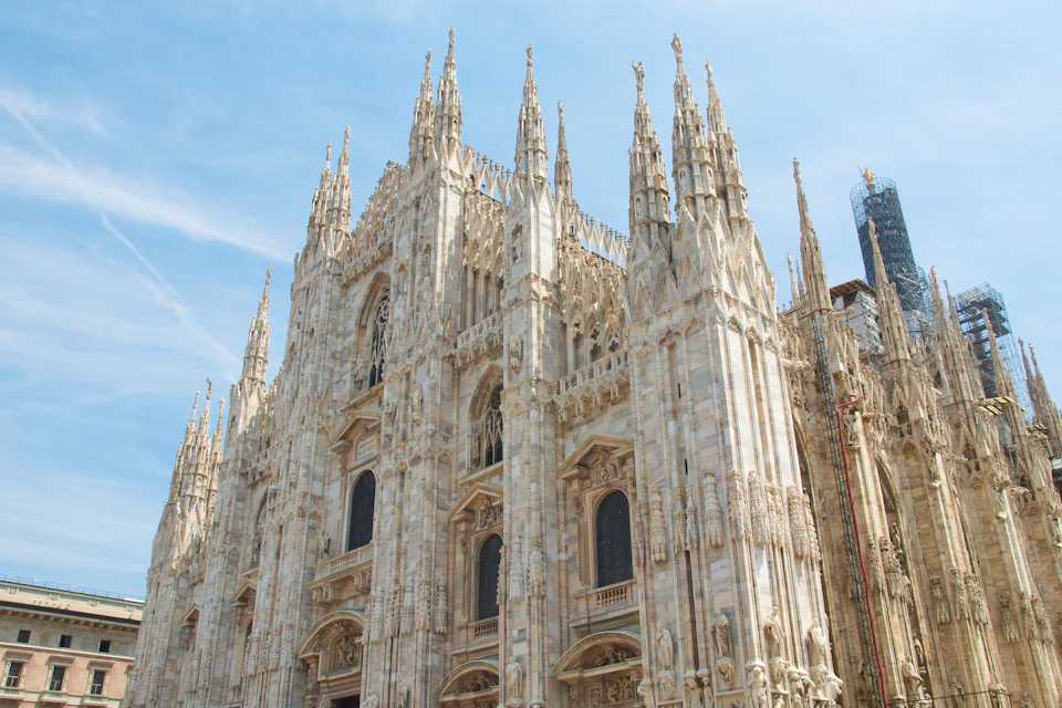 Gothic cathedral with intricate stone carvings and numerous spires under a clear blue sky.