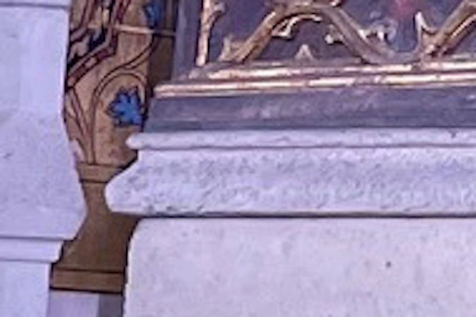 People observing an ornate religious display inside a cathedral, with stained glass and paintings visible in the background.