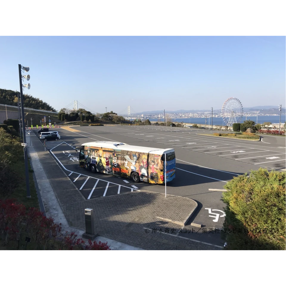 A nearly empty parking lot with a colorful bus, a white van, and glimpses of a Ferris wheel and a bridge in the background under a clear sky.