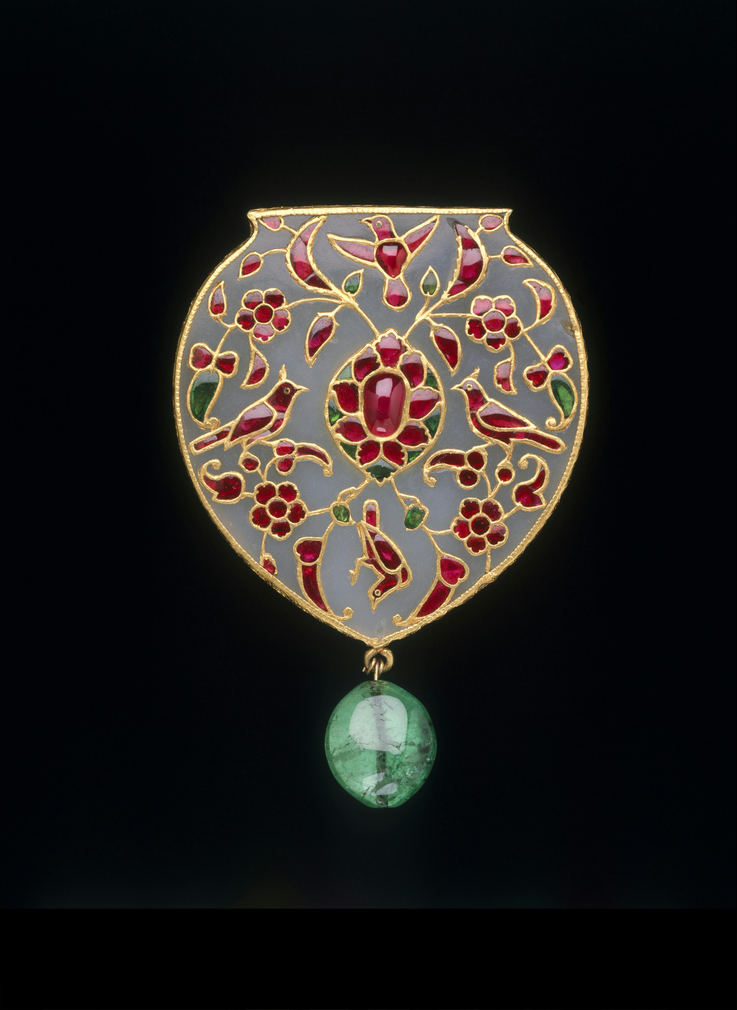 A decorative shield-shaped ornament with floral and bird motifs in red and green, featuring a dangling green bead.
