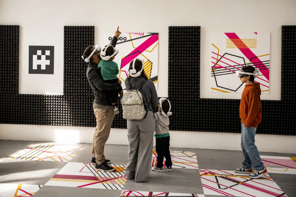 A group of people wearing VR headsets interact in a room featuring abstract art and acoustic wall panels.