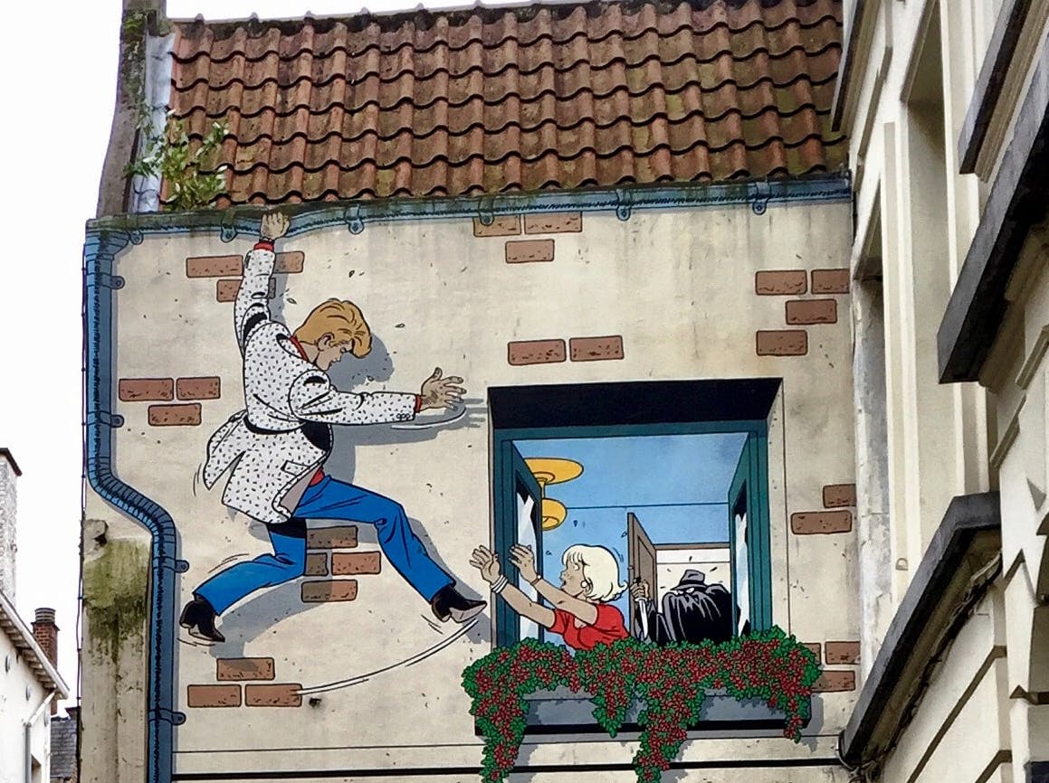 Barevná nástěnná malba muže lezoucího po zdi směrem k otevřenému oknu, kde se k němu natahuje žena s blond vlasy.