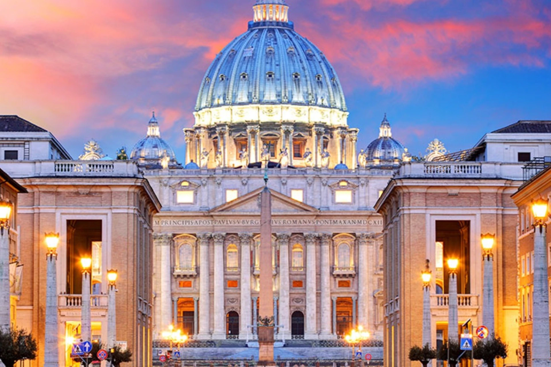 St. Peter's Basilica illuminated at dusk with a clear view of the dome, facade, and obelisk in Vatican City.