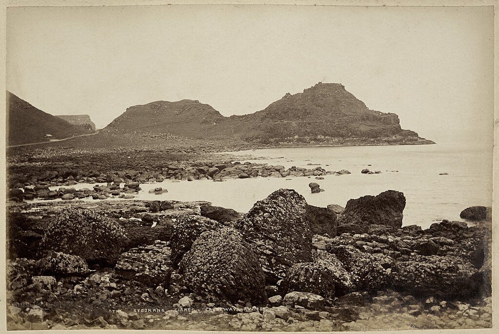 沿海景观，海岸上有巨大的岩层，导致一个多岩石的丘陵岛屿在多云的天空下延伸到大海中。