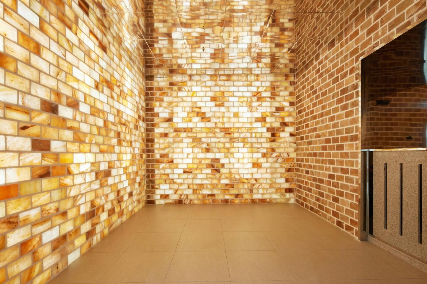 A room with walls made of illuminated salt bricks and a tiled floor, creating a warm and glowing atmosphere.