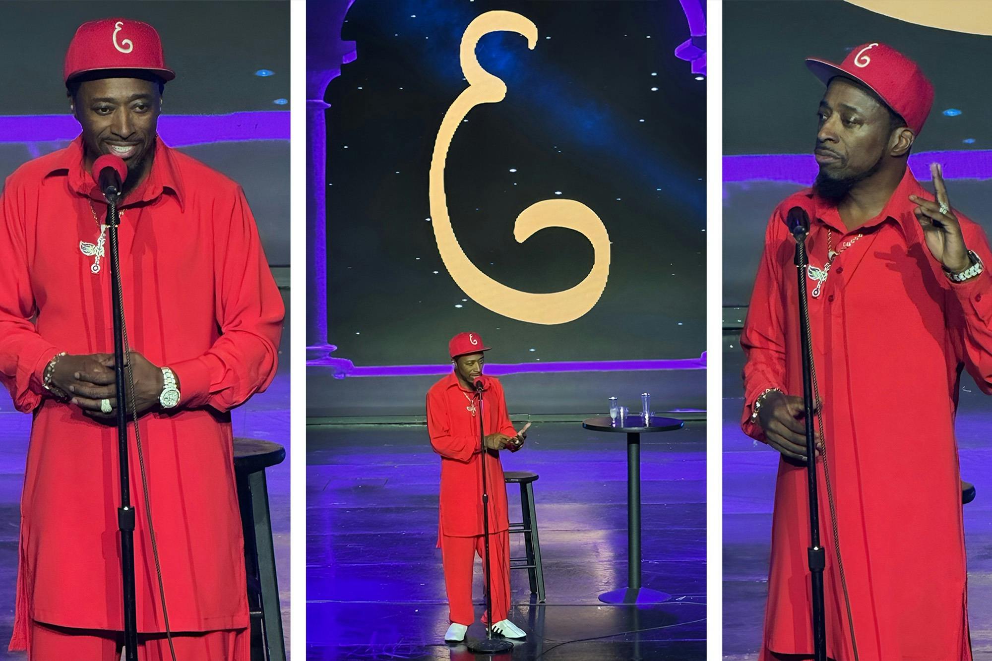 A person in red attire stands on stage with a microphone, in front of a large decorative backdrop, under stage lighting.