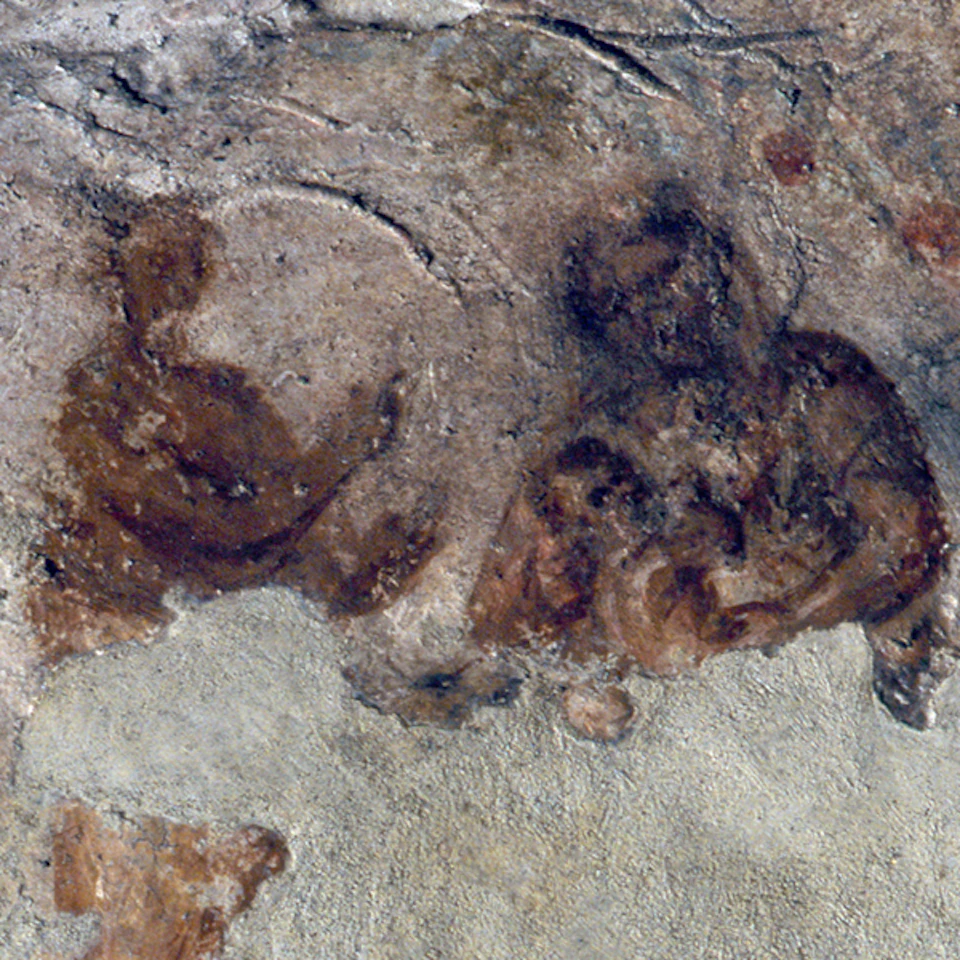 Ancient cave painting depicting two indistinct human figures on a rough, textured stone surface.