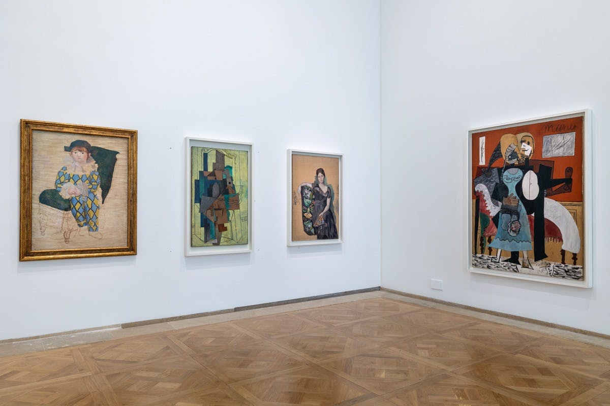 Gallery wall displaying three framed artworks of various styles on a wooden parquet floor.