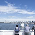 Hosté na lodi Argosy Cruises sledující plachetnici s panoramatem v pozadí