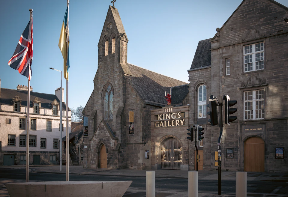 Stone building with gothic architecture labeled "The King's Gallery." Flag and traffic lights visible in the foreground.