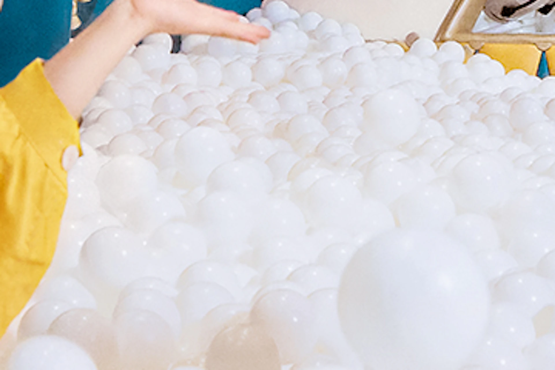 Two children playing in a ball pit with colorful decorations and signs for a maze and slide in the background.