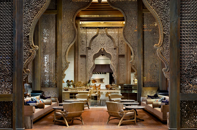 Luxurious interior with ornate arches, intricate carvings, and elegant seating areas with wooden furniture and cushions.
