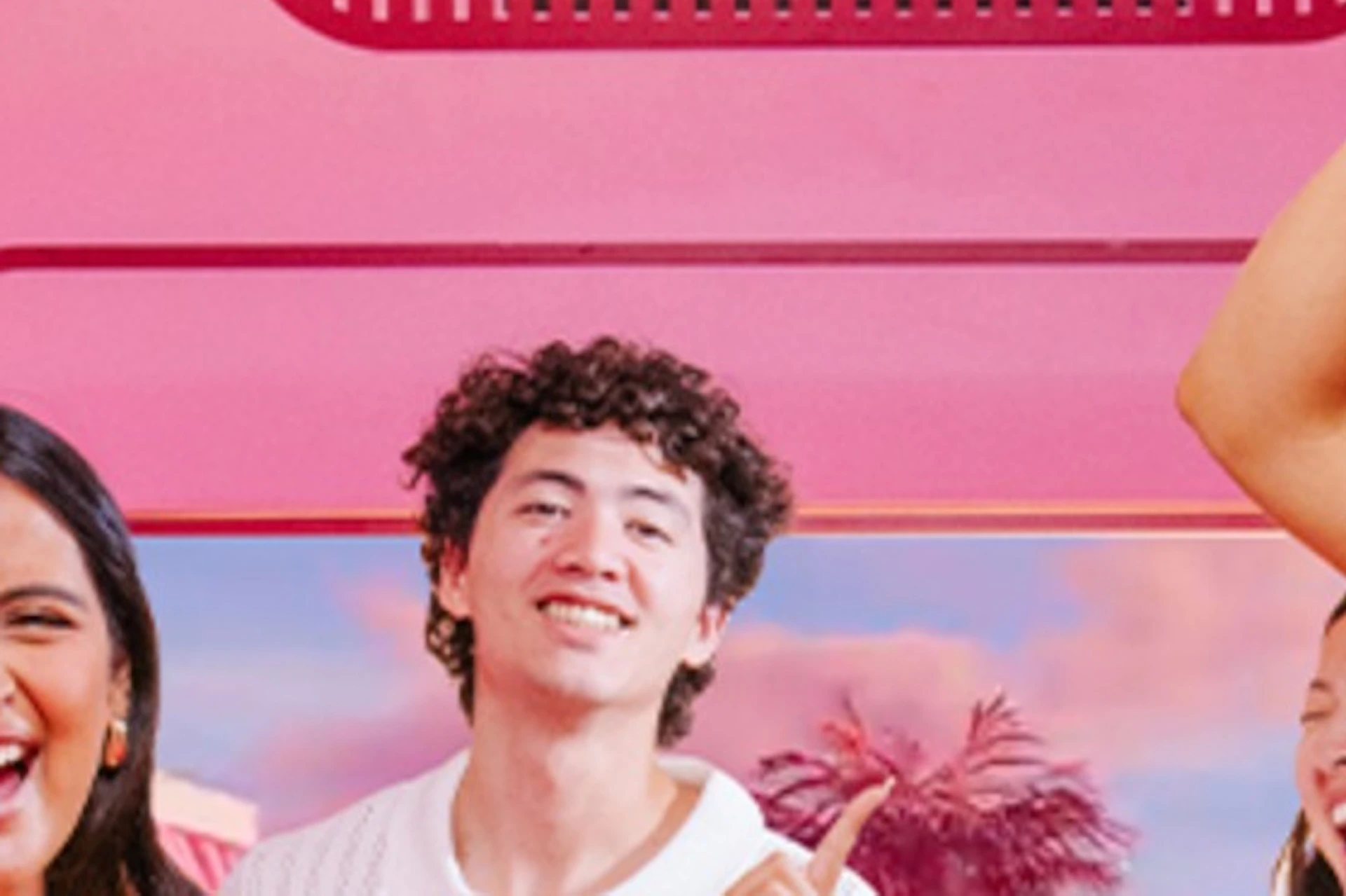 A group of people smiling and holding ice cream cones in a colorful, pink-themed room with decorative elements.